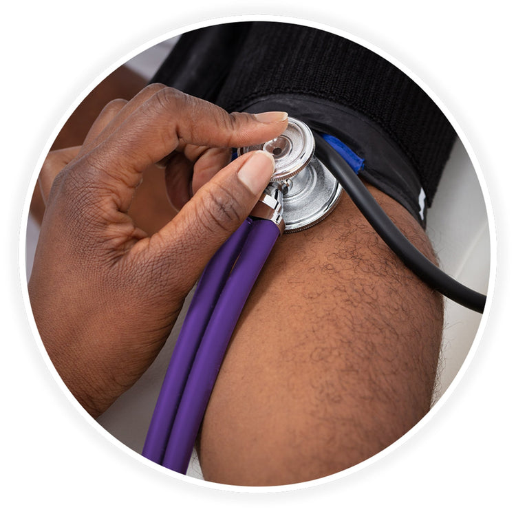 A close-up photo demonstrating a medical examination. A dark-skinned healthcare professional's hand is shown using the purple stethoscope to check a patient's blood pressure, placing the chest piece against the arm just below a black blood pressure cuff.