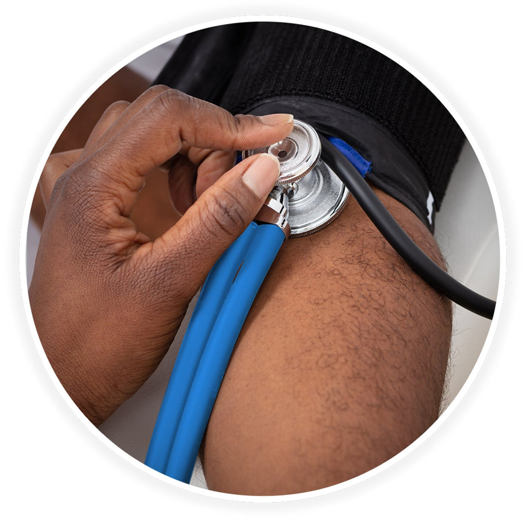 A close-up photo demonstrating a medical examination. A dark-skinned healthcare professional's hand is shown using the sea breeze stethoscope to check a patient's blood pressure, placing the chest piece against the arm just below a black blood pressure cuff.