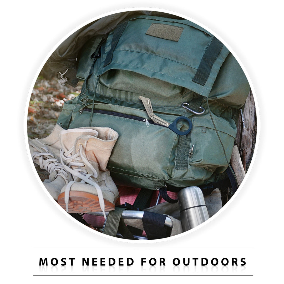A lifestyle image titled "MOST NEEDED FOR OUTDOORS" showing hiking gear. A pair of navy blue-handled trauma shears is tucked into the zippered pocket of a green hiking backpack, which sits next to tan boots and a stainless steel flask, illustrating the tool's utility for outdoor survival.