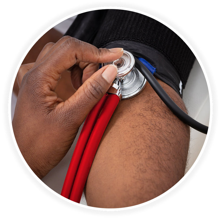 A close-up photo demonstrating a medical examination. A dark-skinned healthcare professional's hand is shown using the red stethoscope to check a patient's blood pressure, placing the chest piece against the arm just below a black blood pressure cuff.