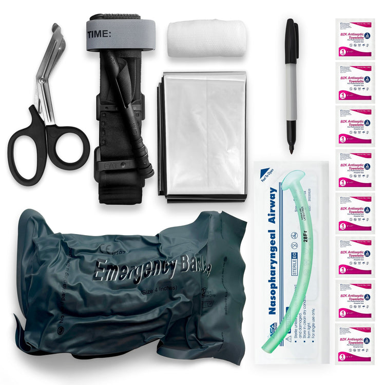 A flat lay photograph of a first aid kit's components arranged on a white background. The items include black trauma shears, a black combat tourniquet, a roll of white gauze, a folded silver emergency blanket, a black marker pen, a packaged nasopharyngeal airway, a grey vacuum-sealed emergency bandage, and eight small packets of BZK antiseptic towelettes.