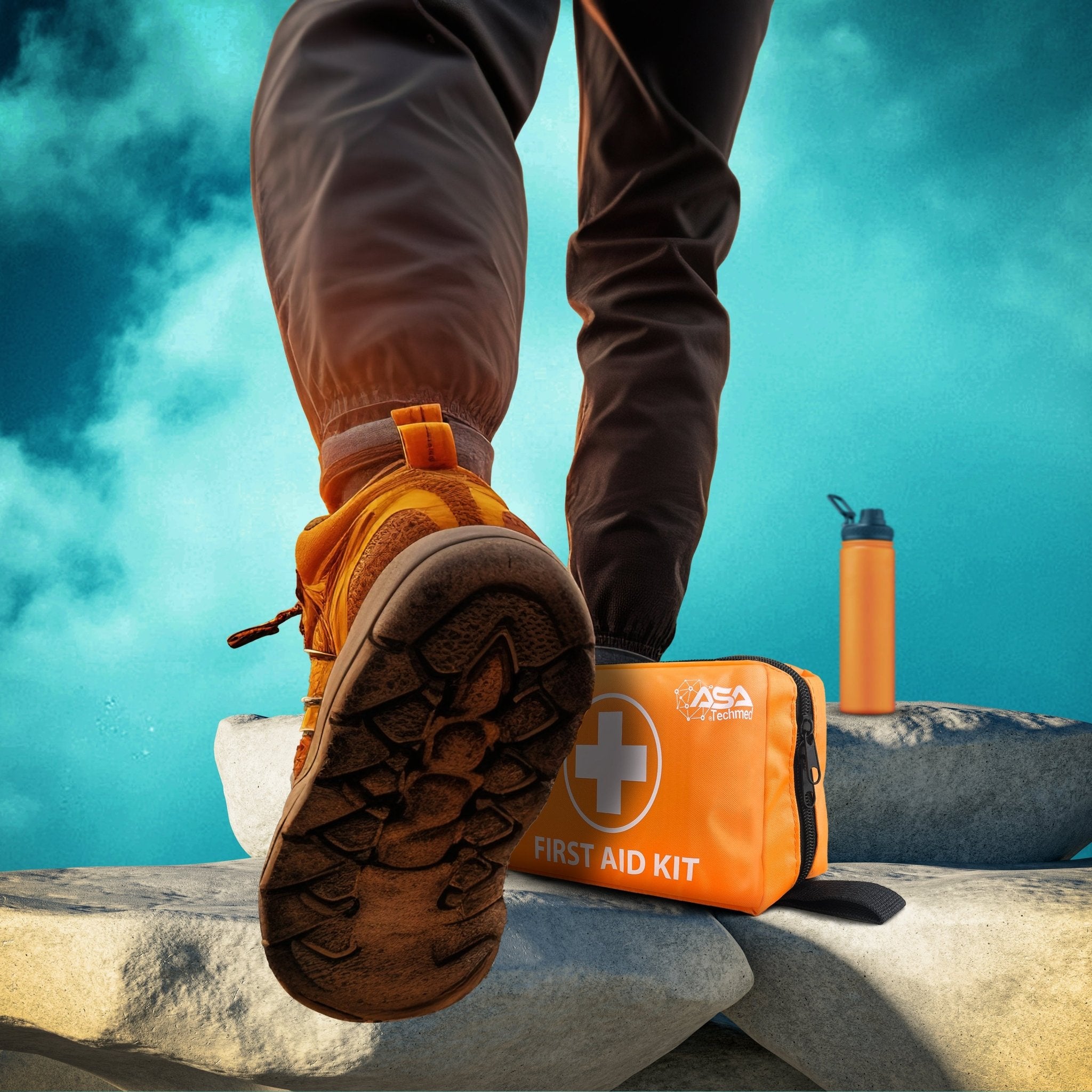 A low-angle lifestyle shot focusing on the hiking boots of a person stepping onto large rocks against a blue sky. Next to their feet rests the orange "ASA Techmed" first aid kit and an orange water bottle.