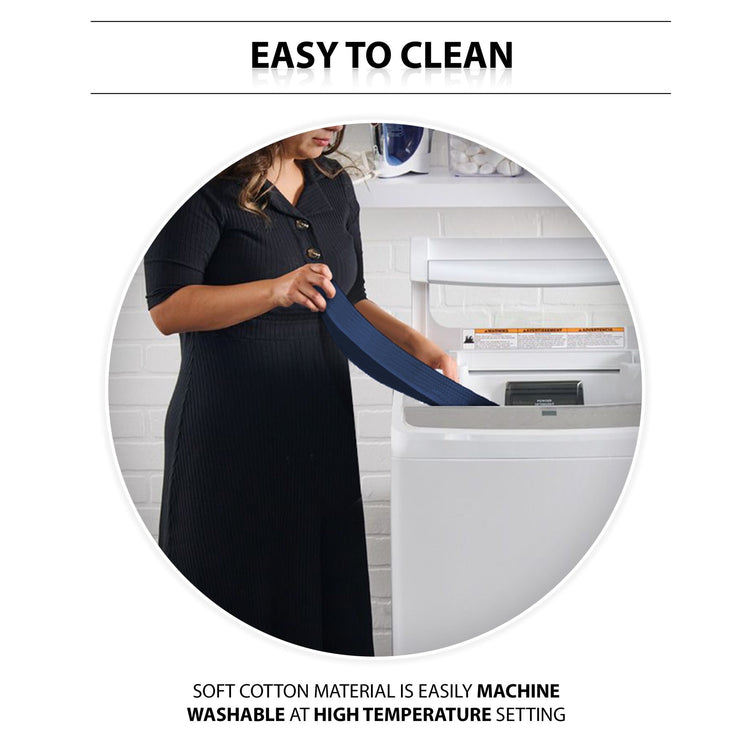 An instructional lifestyle image titled "EASY TO CLEAN." A woman is shown standing in a laundry room, placing the navy blue gait belt into a white top-loading washing machine. Text at the bottom highlights the care instructions: "SOFT COTTON MATERIAL IS EASILY MACHINE WASHABLE AT HIGH TEMPERATURE SETTING."