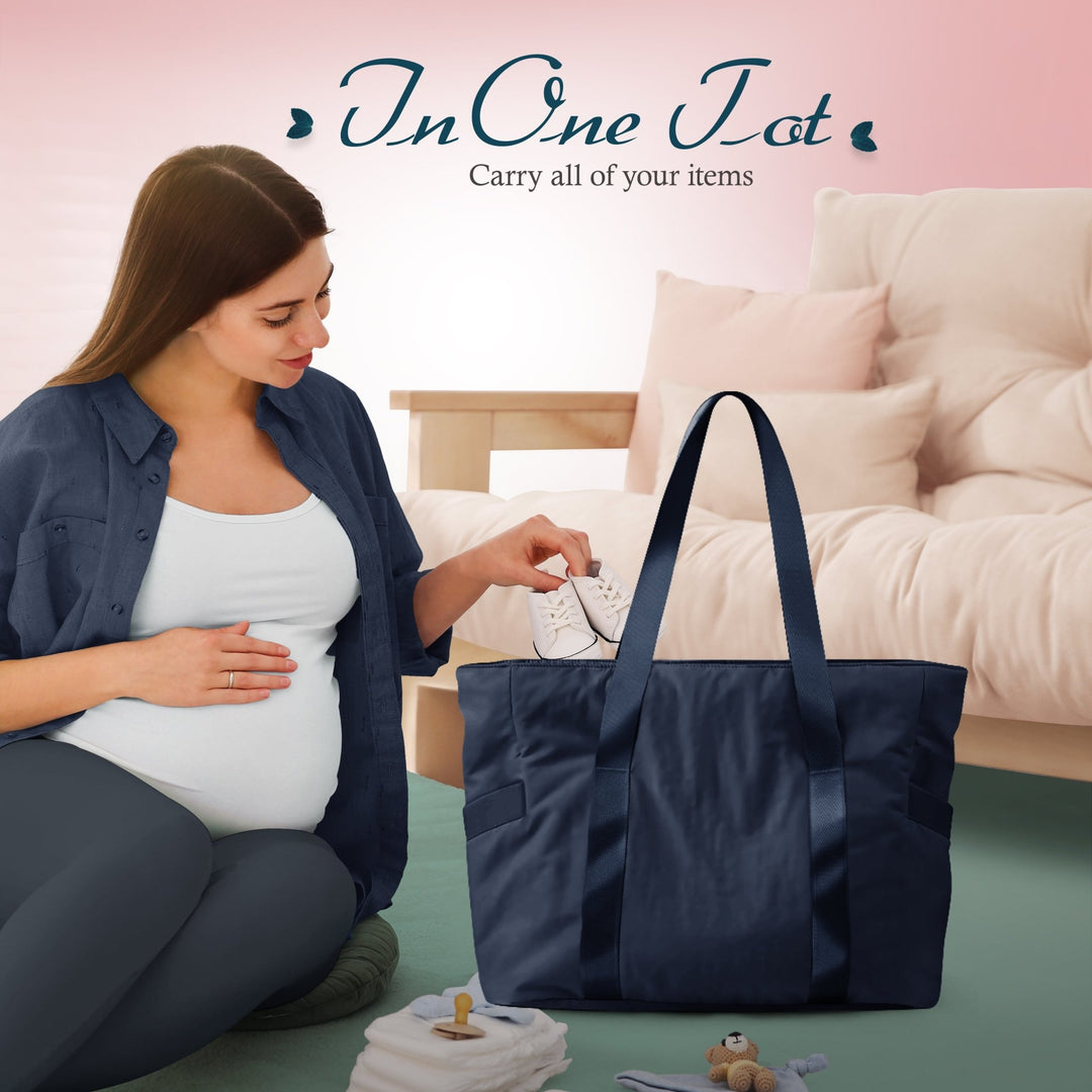 A lifestyle image showing a pregnant woman sitting on the floor, placing small white baby shoes into the open navy blue tote bag. The text above reads, "In One Tote Carry all of your items," suggesting its use as a diaper or hospital bag.