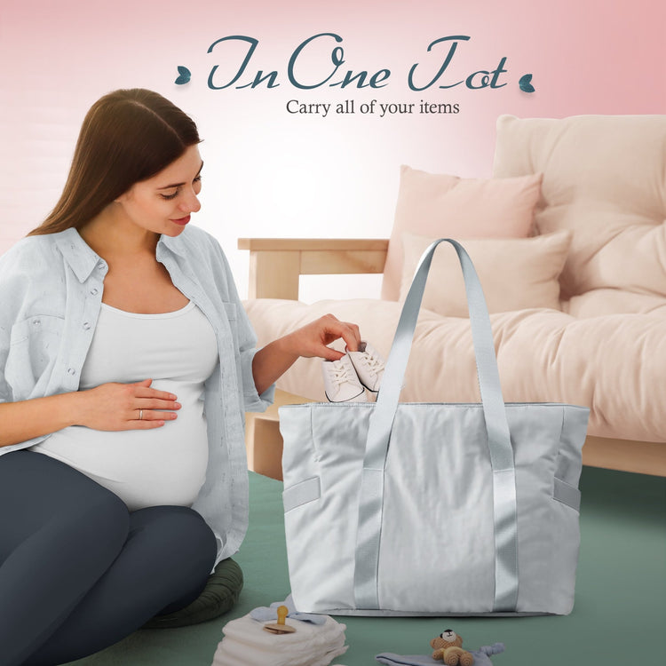 A lifestyle image showing a pregnant woman sitting on the floor, placing small white baby shoes into the open gray tote bag. The text above reads, "In One Tote Carry all of your items," suggesting its use as a diaper or hospital bag.